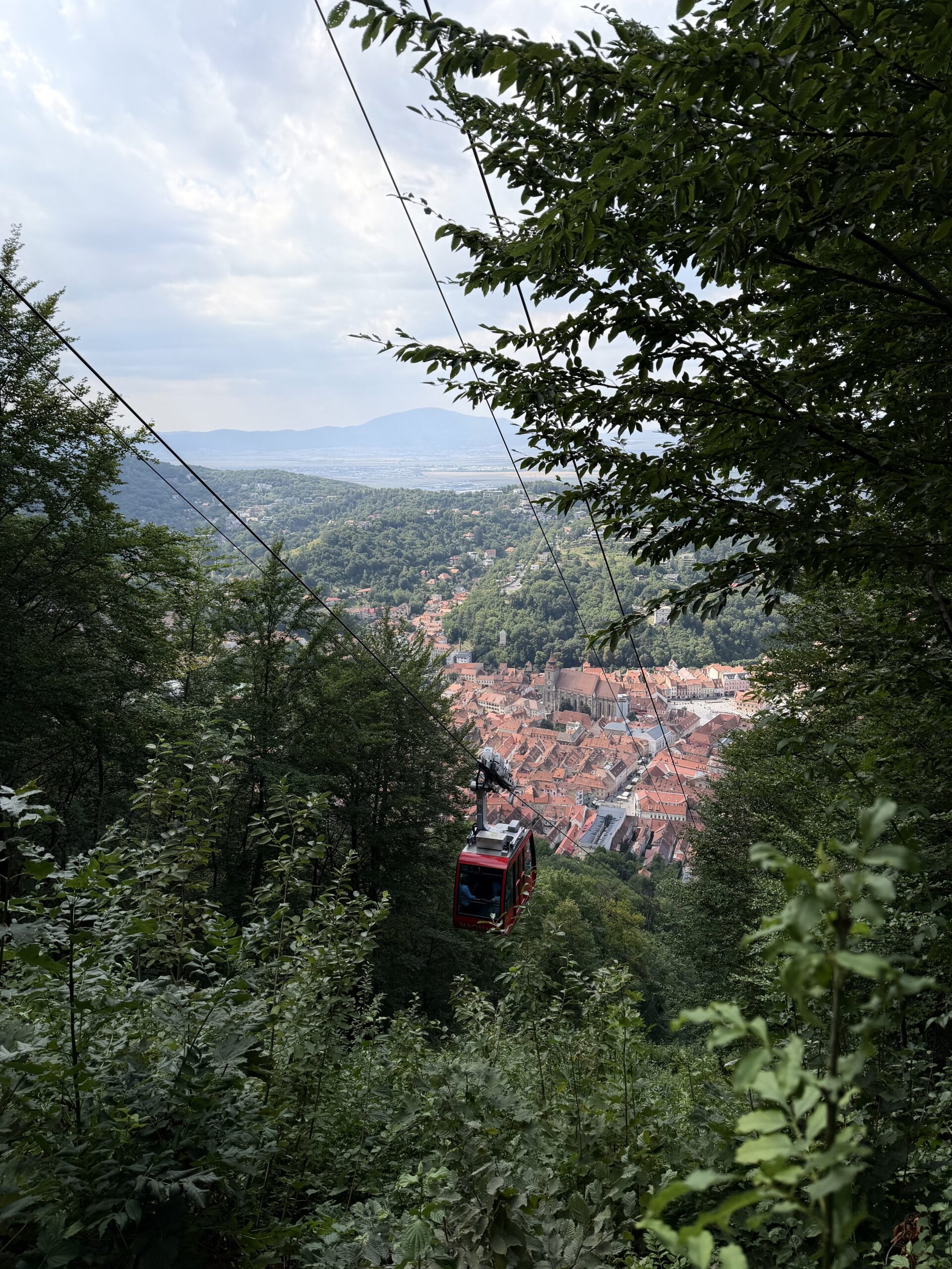 Que voir et que faire à Brașov ? Guide complet & Conseils Vue sur Brasov et une télécabine depuis le sentier des Serpentines en redescendant du mont Tâmpa